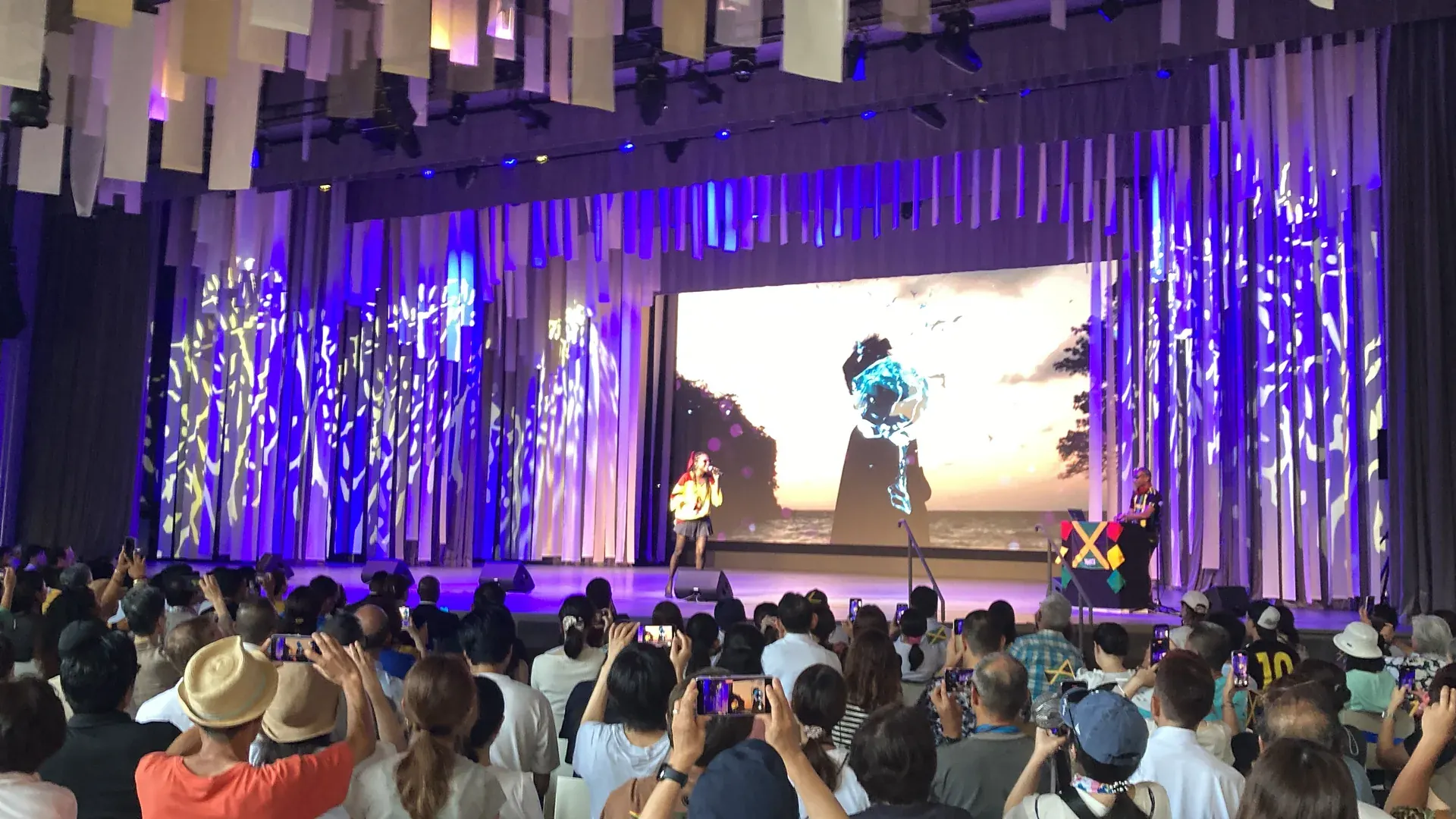 夕景のスクリーンを背にした屋外ステージ公演