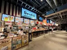 大阪のれんめぐり 〜食と祭EXPO〜。串かつだるまの店舗看板と、店頭でたこ焼きを焼くスタッフ