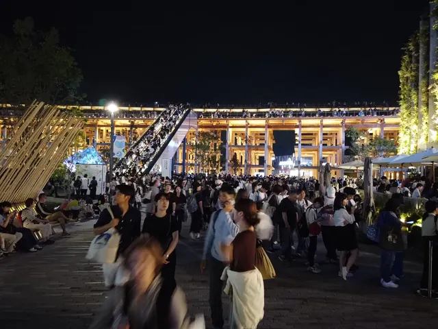 夜の大屋根リング下、階段の観客と広場を歩く来場者