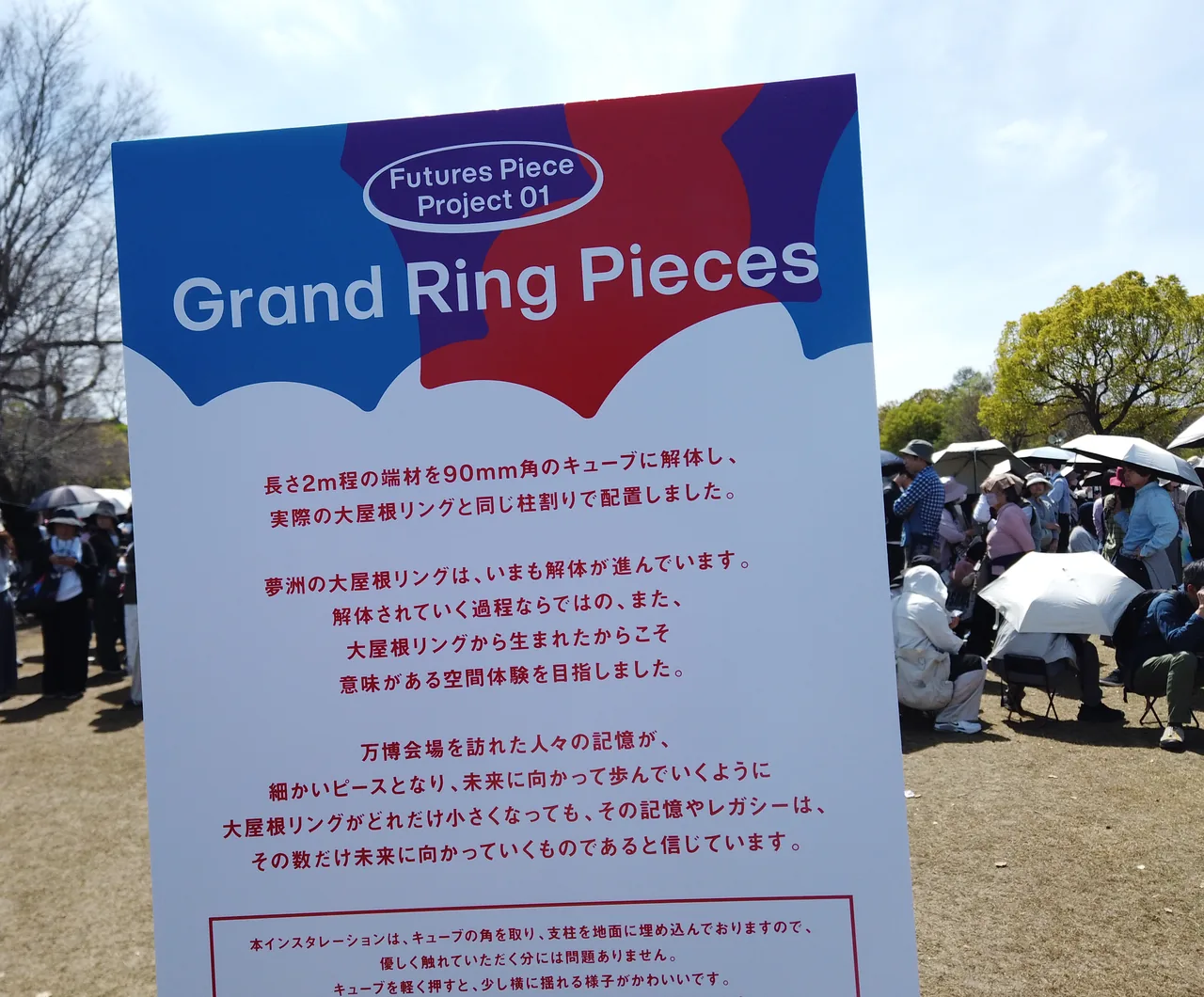 「Grand Ring Pieces」の説明板。大屋根リングの端材を90mm角のキューブに解体して並べた作品の解説が書かれている
