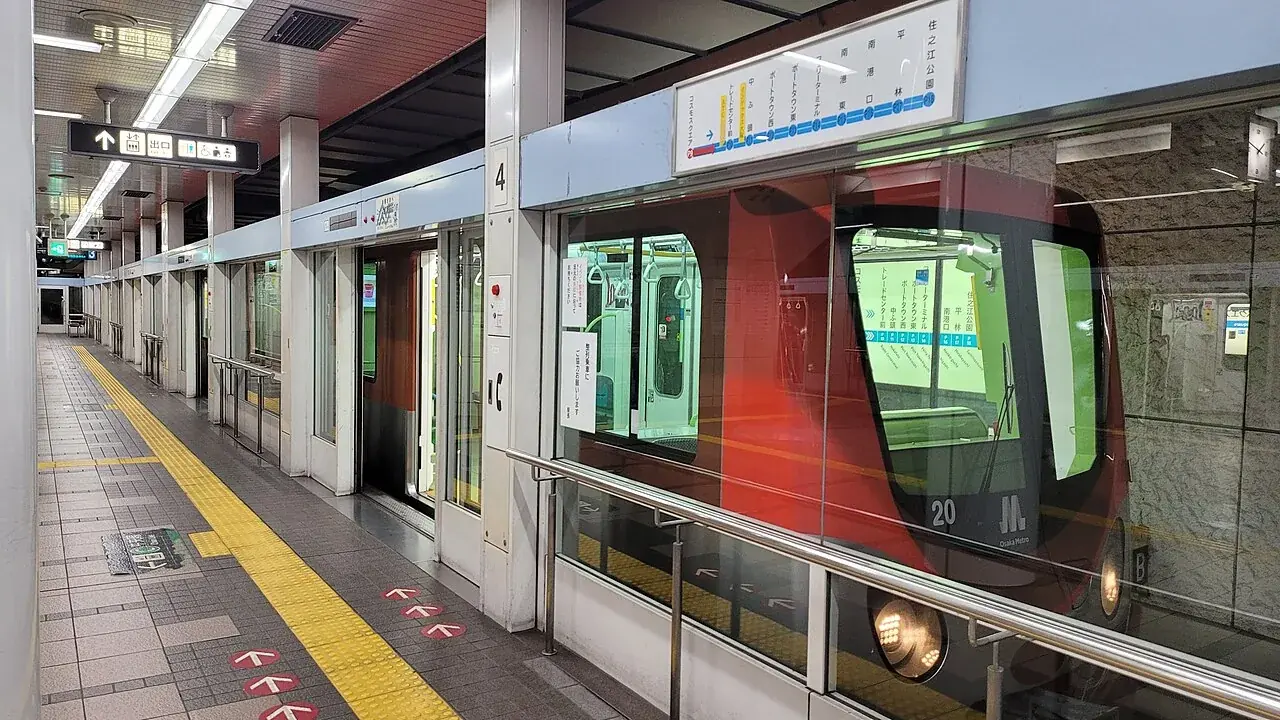 ホームドア越しに停車するOsaka Metroニュートラムの赤い車両