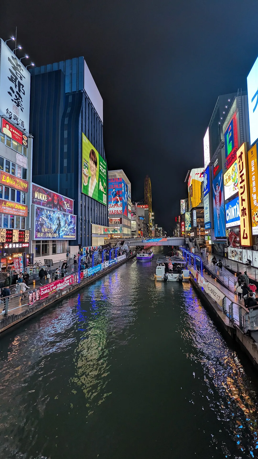 夜の道頓堀川。両岸を色とりどりの看板が埋め、水面に光が映り込んでいる