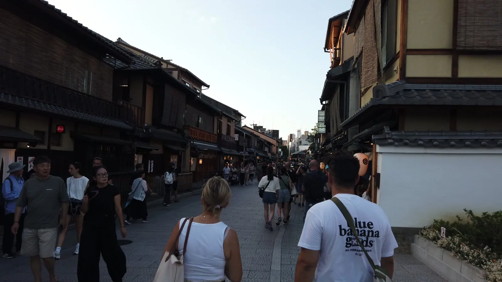 夕暮れの花見小路。石畳の両側に木造の町家が続き、大勢の観光客が歩いている
