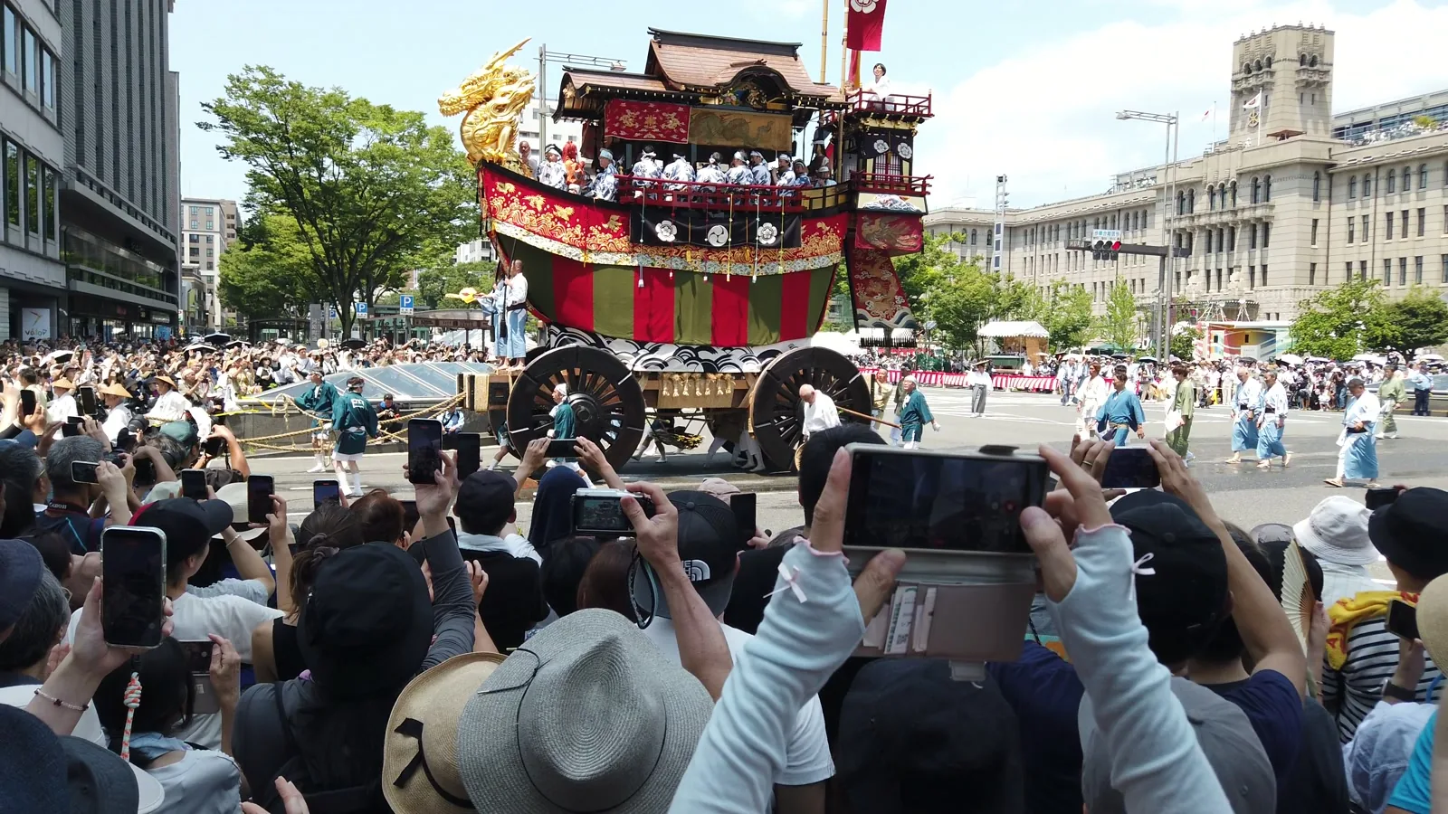 金色の龍頭を船首にかかげた大船鉾。沿道ではスマートフォンを構えた人たちが並んでいる