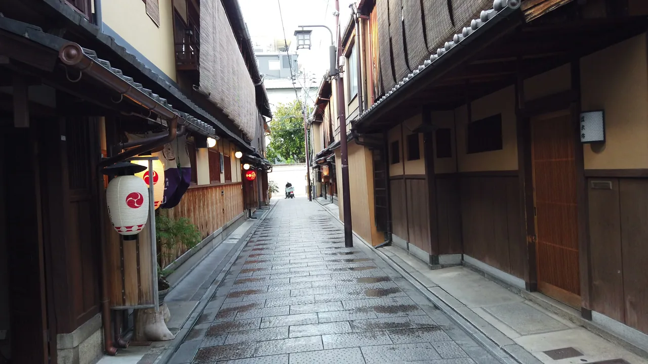 提灯の灯った祇園の石畳の路地。町家の格子が続き、人影はない