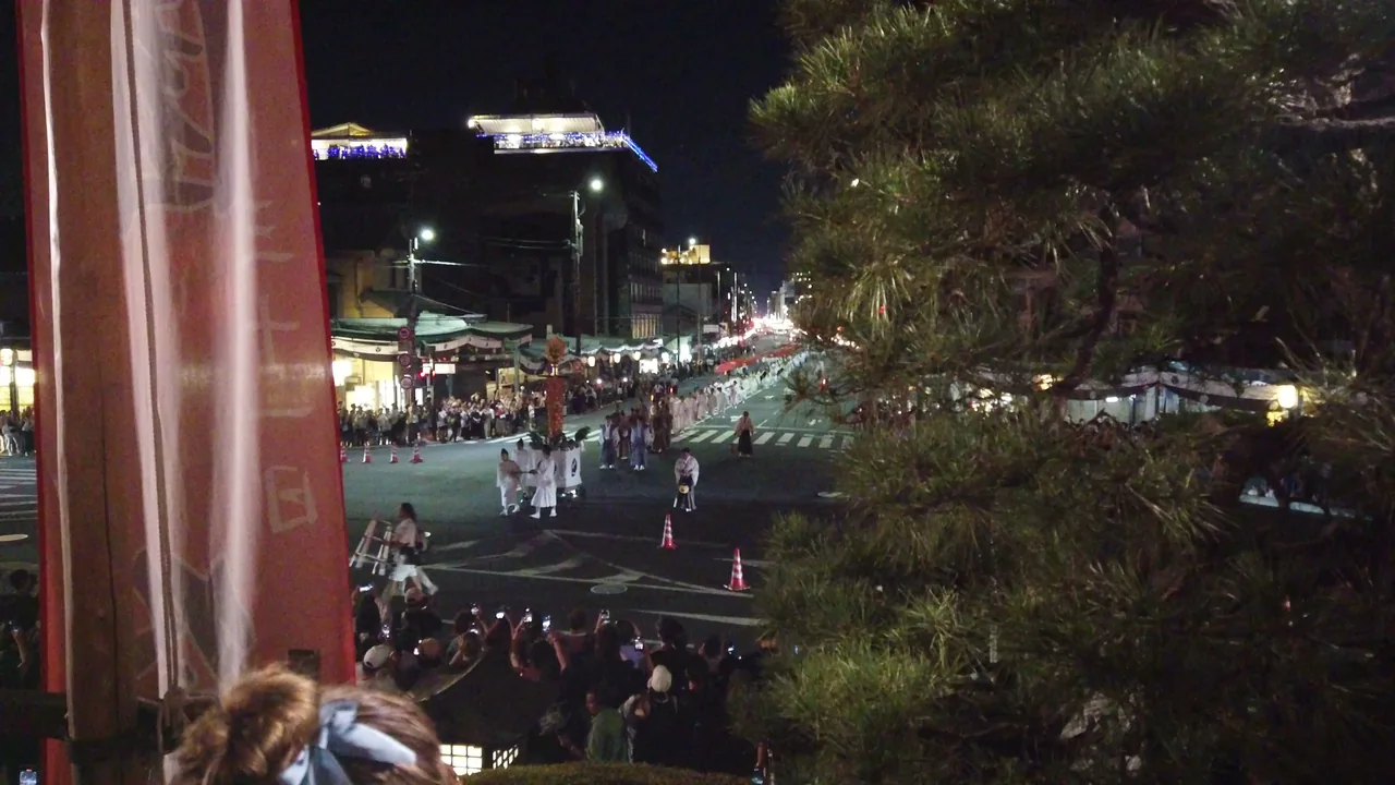 高い位置から見下ろした夜の街路。灯りの下に人の波が続いている