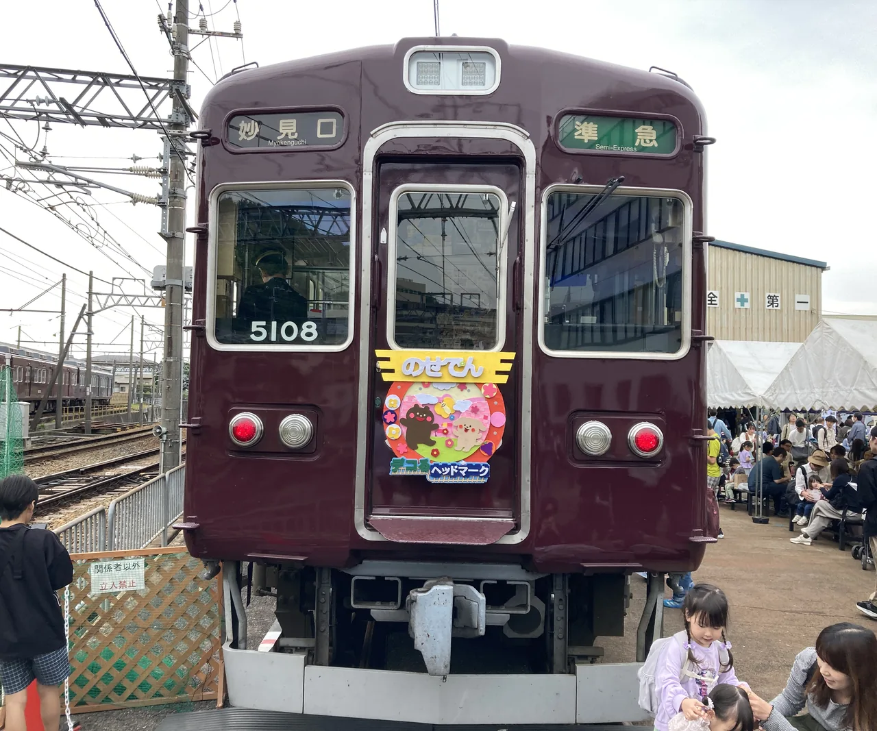 「妙見口」「準急」の表示を出したマルーン色の車両5108の正面。のせでんのヘッドマークが付いている