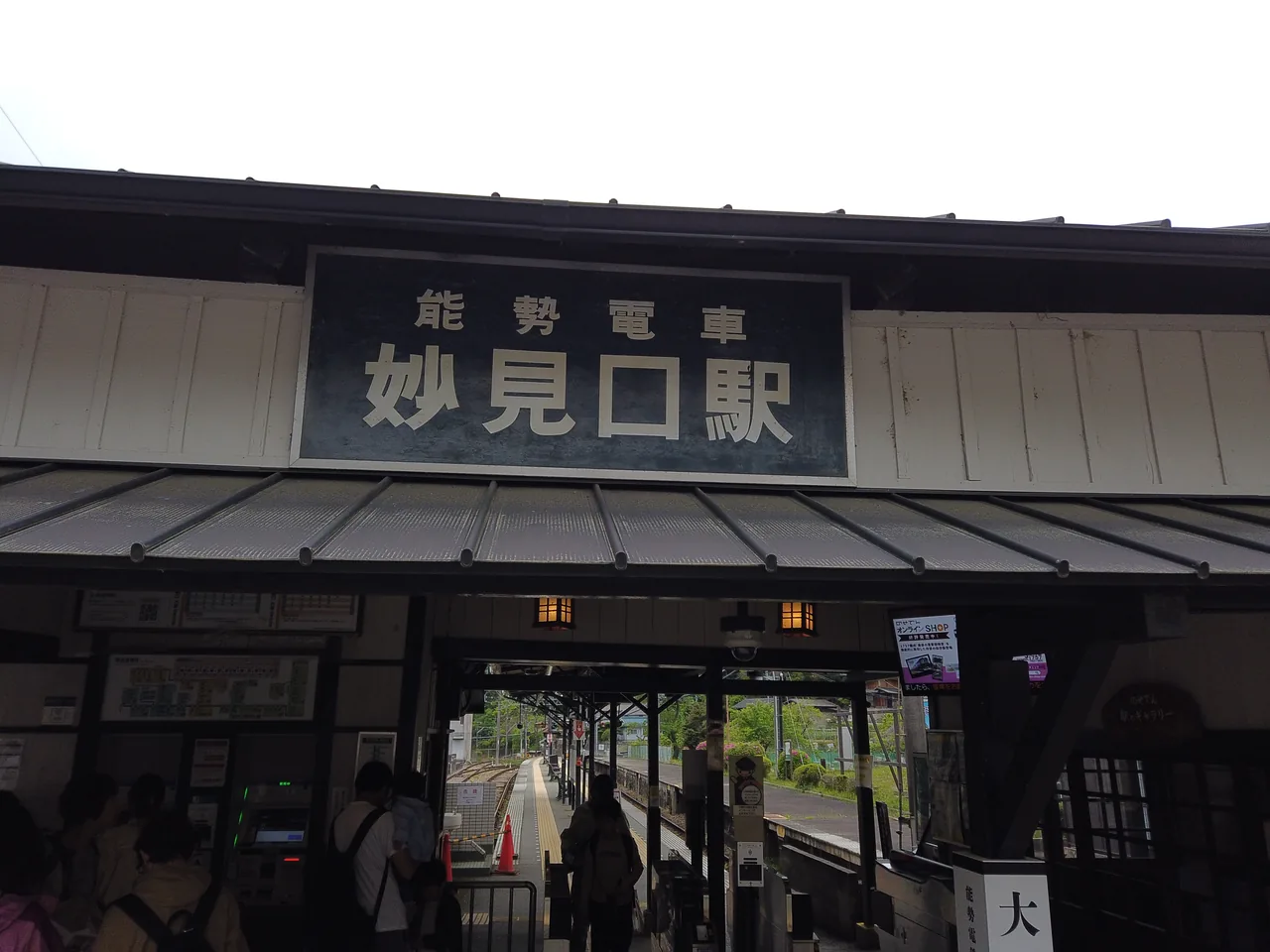 「能勢電車 妙見口駅」の駅名看板がかかる駅舎の軒先
