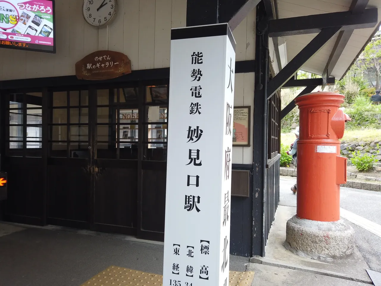 能勢電鉄 妙見口駅の駅舎と「妙見口駅」の縦看板、駅前に立つ赤い丸型ポスト