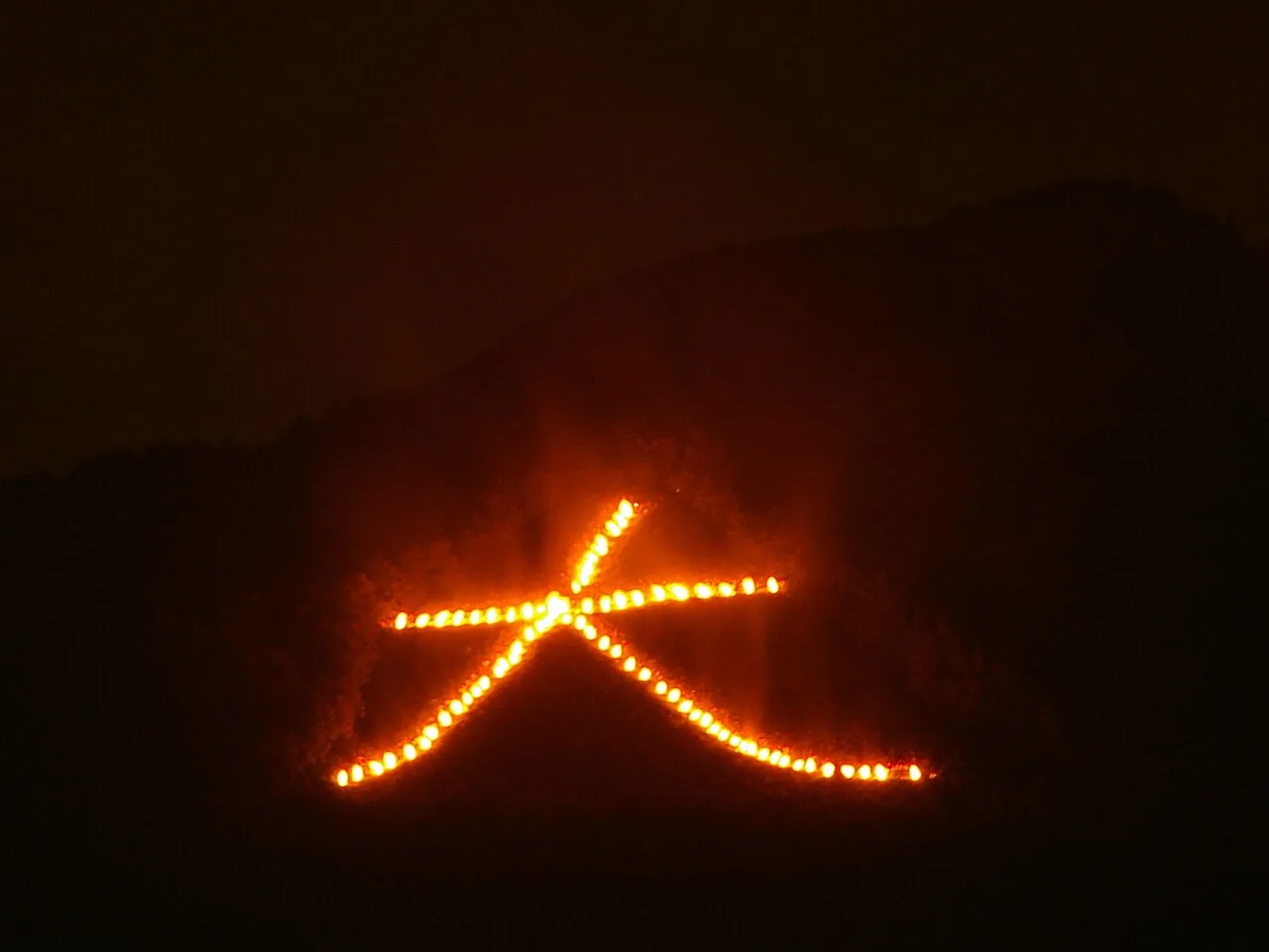 夜の京都、大文字山に浮かび上がる五山送り火の「大」の字