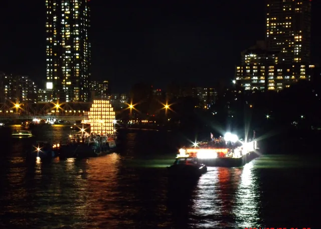 夜の大川に浮かぶ、かがり火と提灯を灯した船