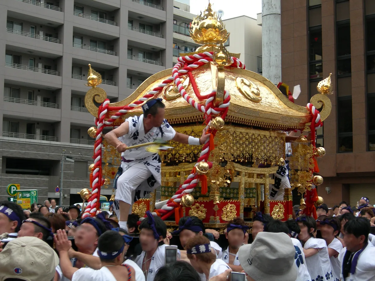 金色に輝く玉神輿を、白装束の担ぎ手たちが担ぎ上げる陸渡御のようす