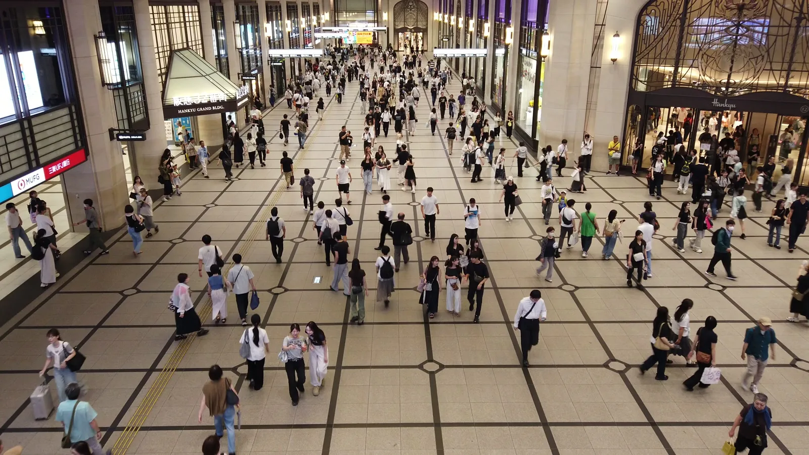 阪急側の広いコンコースを行き交う大勢の人。左右にビルの入口が並ぶ