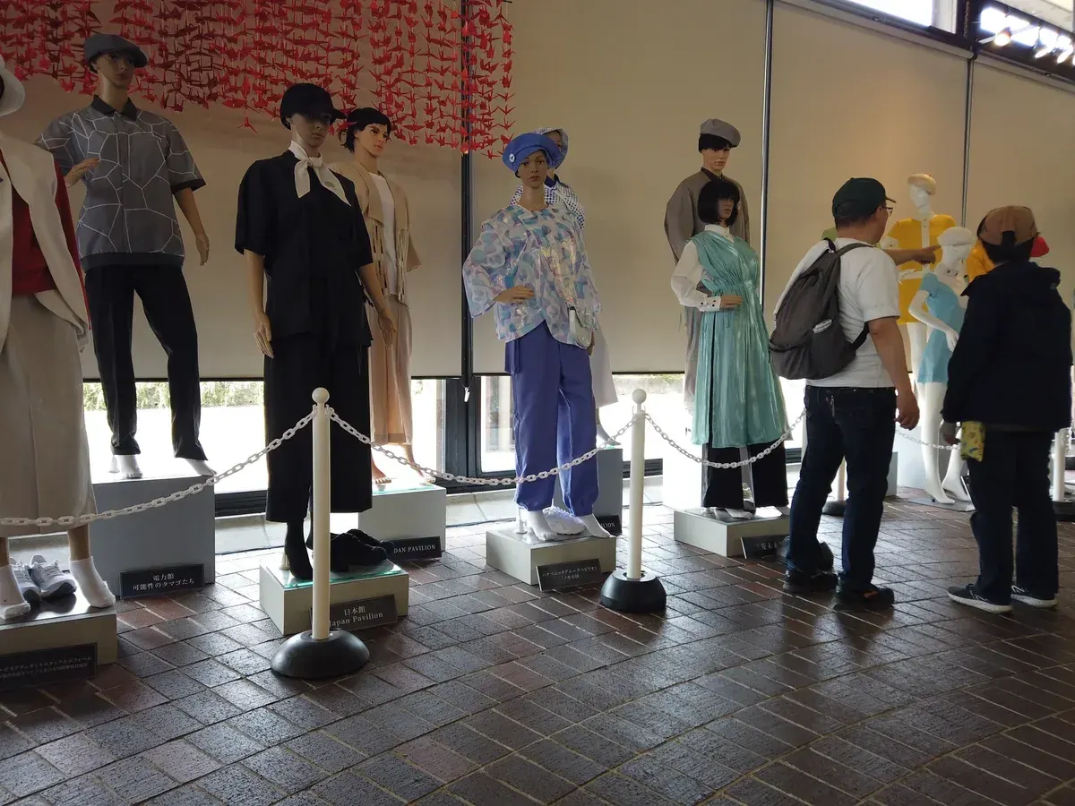 千羽鶴の下に並ぶ、万博各パビリオンのスタッフ制服を着たマネキン