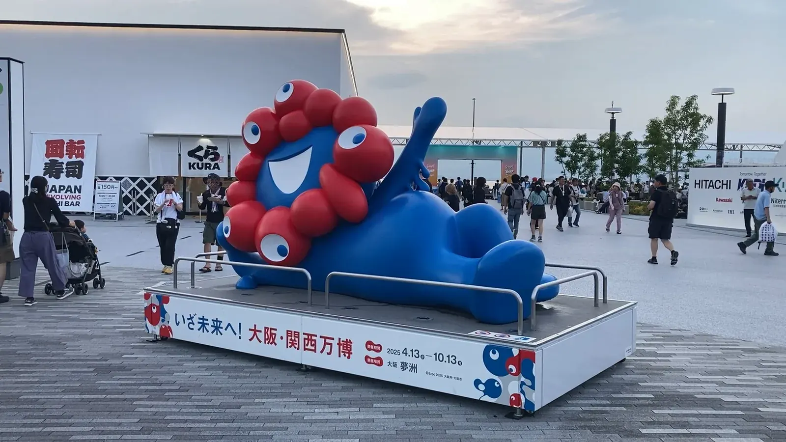 「いざ未来へ！」の台座の上で寝そべるミャクミャクの大型像