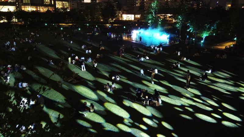 光の模様が映る夜の芝生でくつろぐ人たち