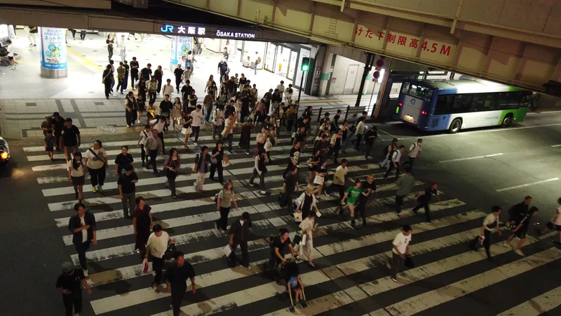 夜のJR大阪駅前の横断歩道を渡る大勢の人
