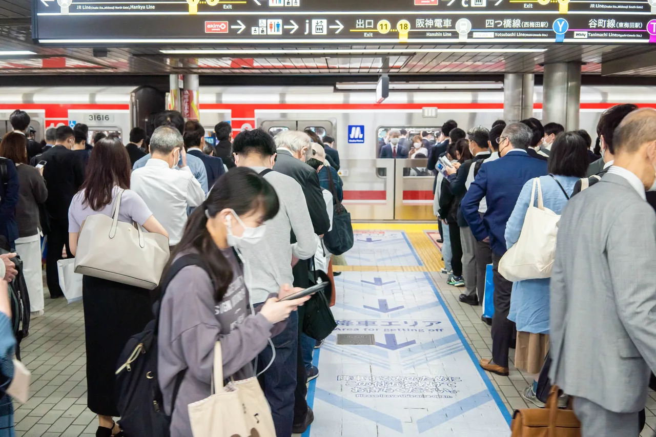 御堂筋線梅田駅ホームで電車を待つ通勤客の行列